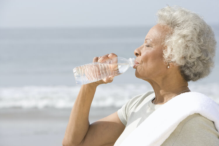 A senior woman drinking water to stay hydrated and boost her immune system.