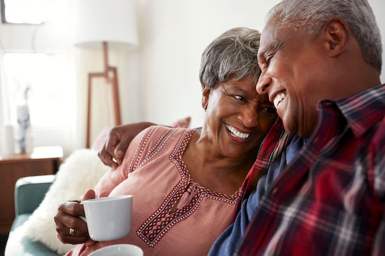 Senior couple sitting on sofa at home. 