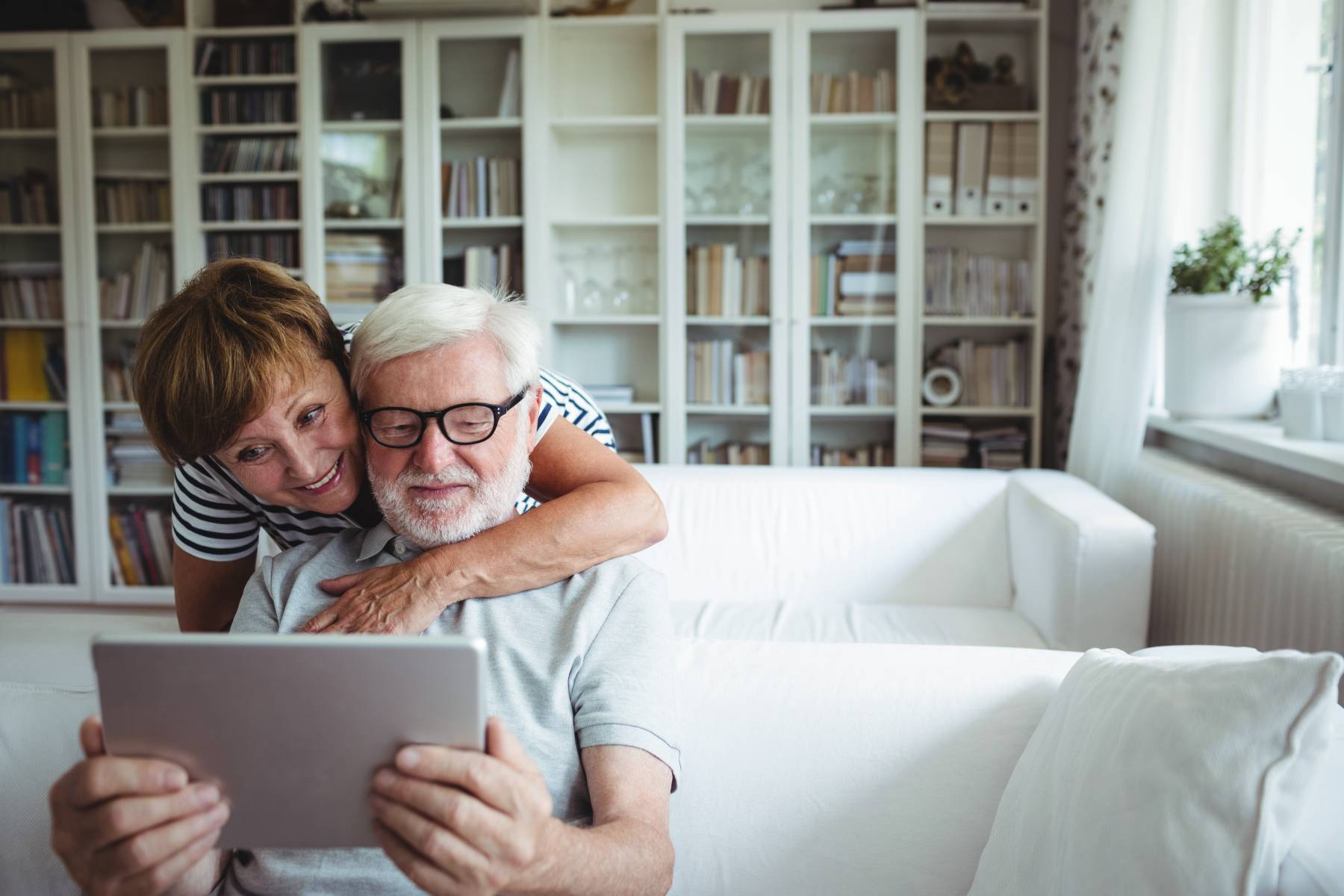 seniors looking at a tablet together while relaxing on the couch
