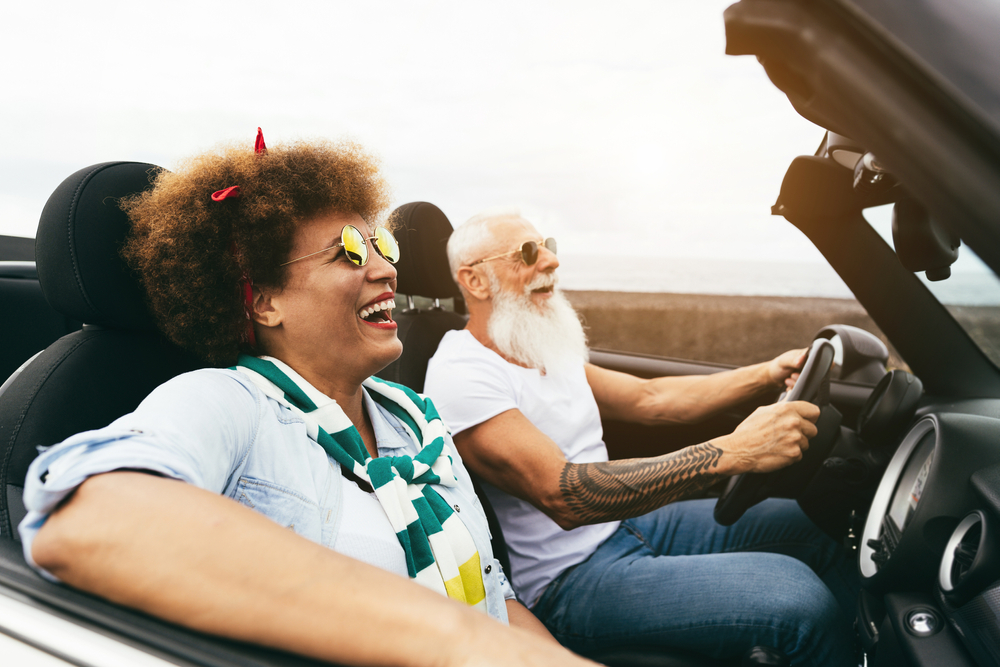 A senior woman and senior man drive a convertible
