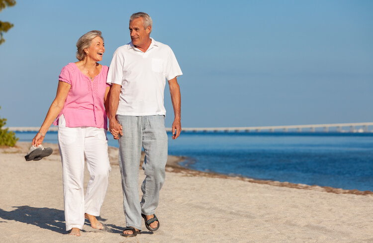 Happy senior couple taking a walk during their vacation on a white sandbeach.