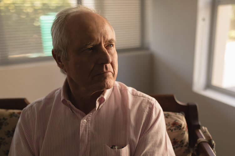 Senior man sitting on chair in home.