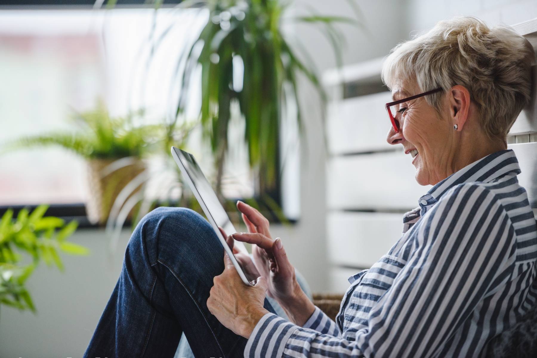 senior looking at a tablet while sitting down and smiling