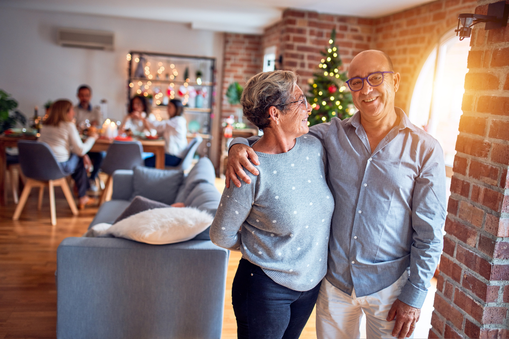 A senior couple pose for a photo in front of a table of family