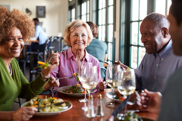 Group of senior friends meet for a meal. 