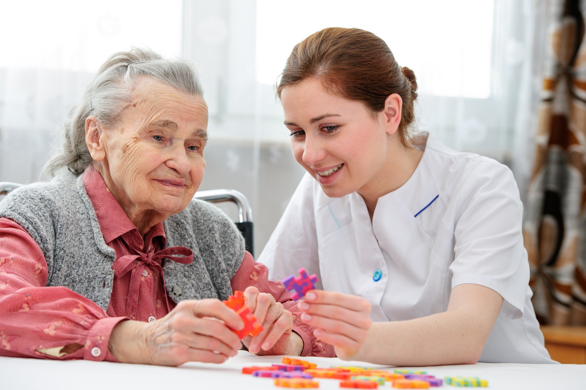 Elderly patient solving a puzzle with a nurse.