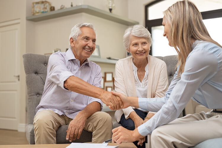 Senior couple thanking Medicare advisor with a handshake.