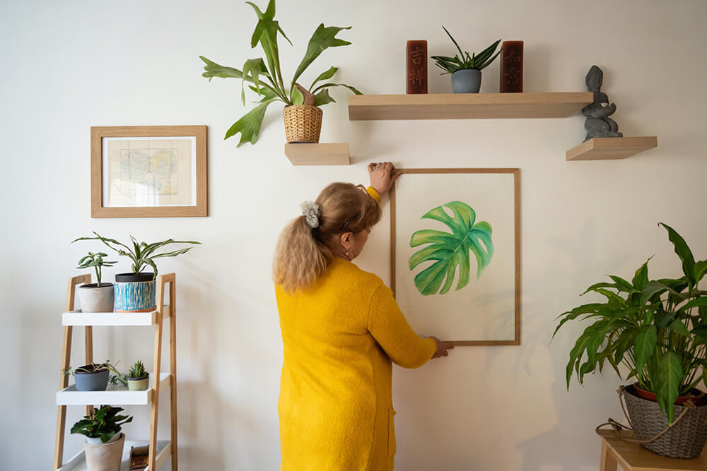 woman hanging artwork on wall