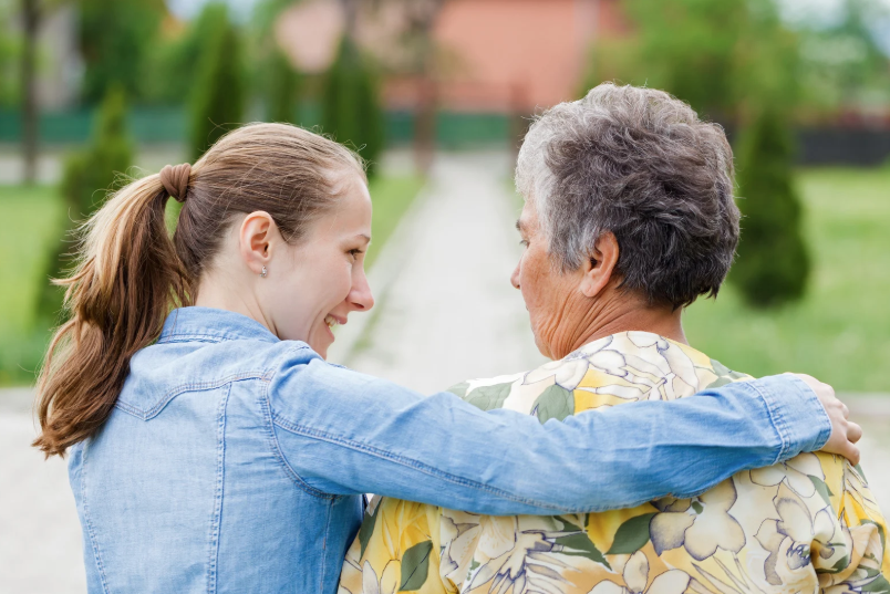 Senior woman and care taker walking down path together