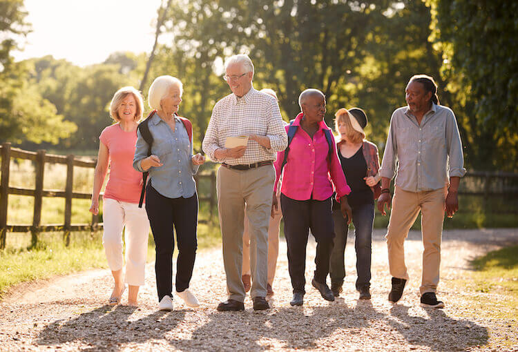 A group of senior friends walking outside on a trail.