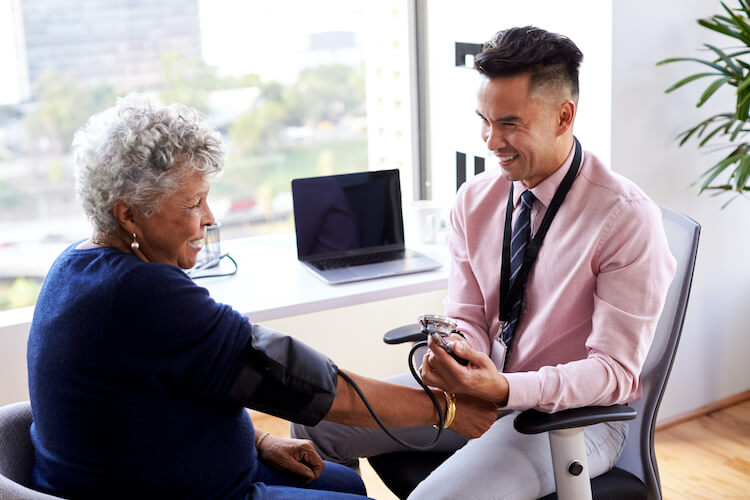 Doctor checking a senior woman’s blood pressure and discussing tips on stroke prevention.