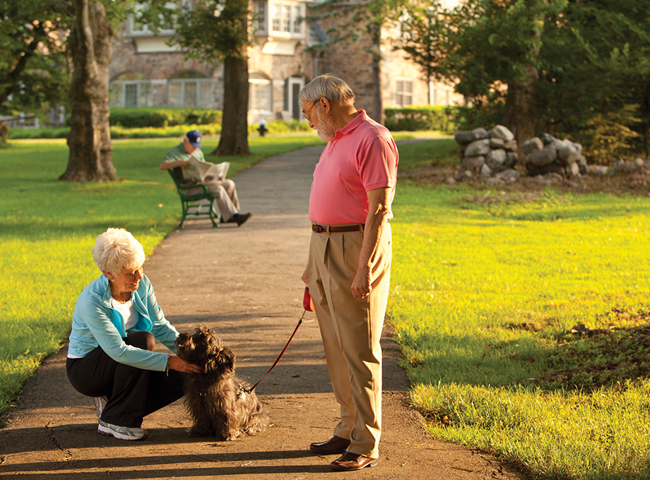 Senior woman pets dog on leash