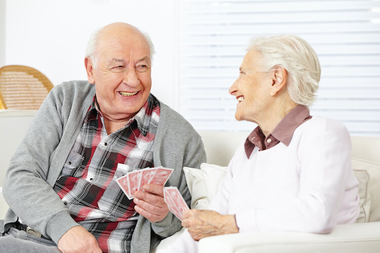 Senior couple playing cards and enjoying their senior living community.