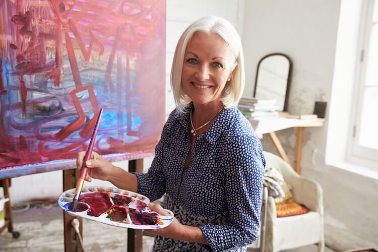 A senior woman painting, one of the many enjoyable hobbies for seniors.