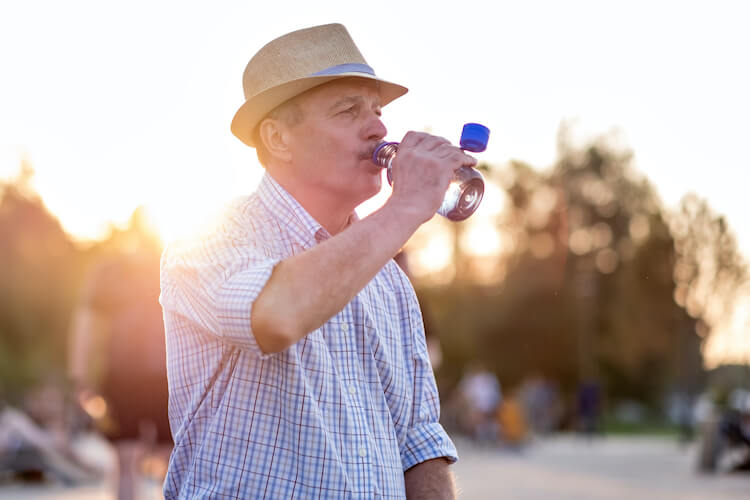 Senior man drinking water to stay hydrated.