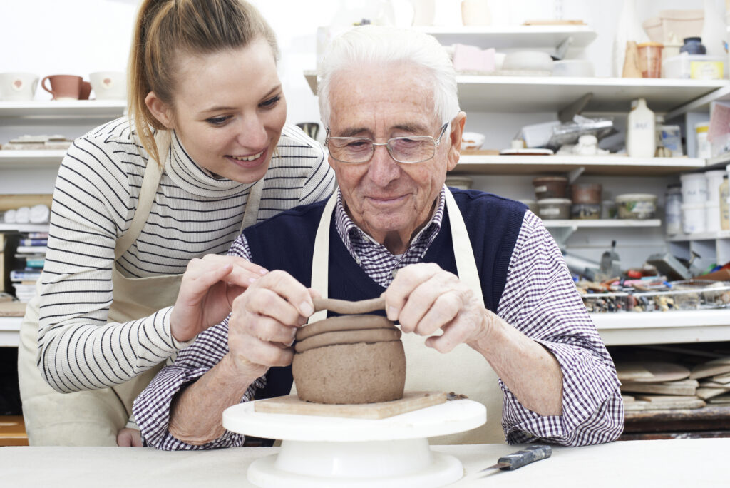 Senior Man With Teacher In Pottery Class
