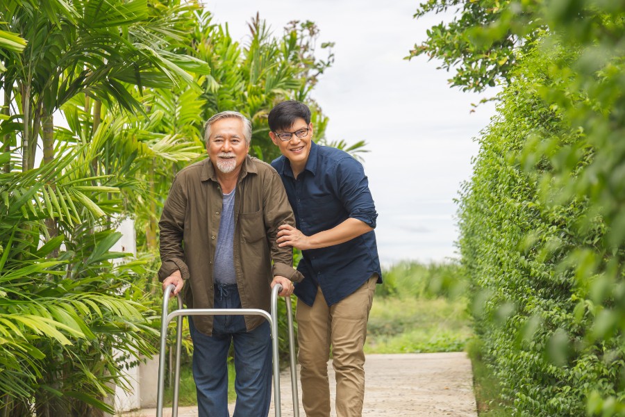 Happy senior man walking with a younger male caregiver