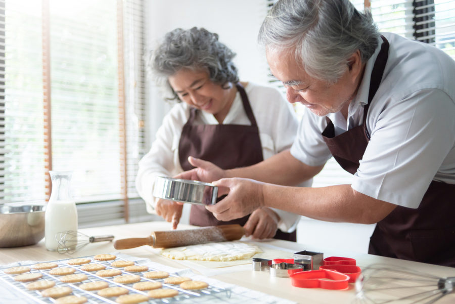 Senior couple baking cookies together to have fun while indoors during the winter months.