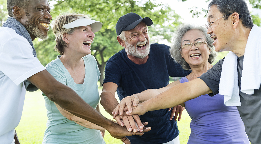 Active Aging Group of seniors participating in exercise program outdoors in the summer.