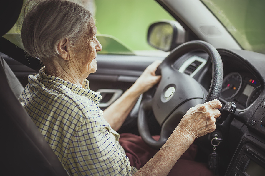An older adult woman is driving a car