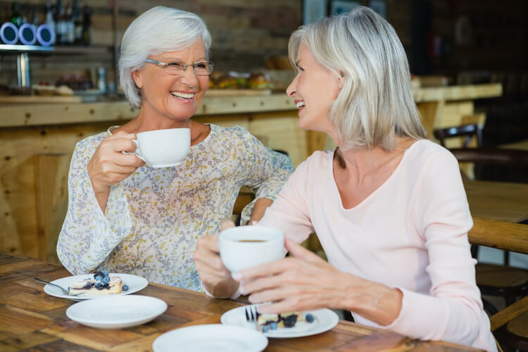 Two senior friends enjoying coffee in a café.