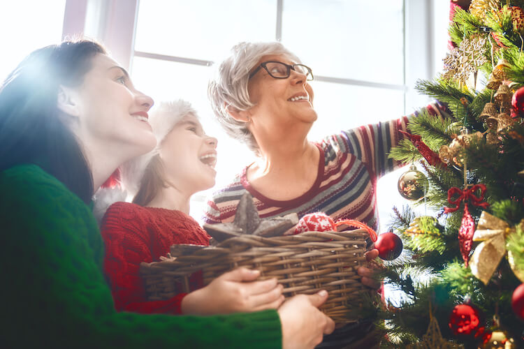 Three generations decorating a holiday tree.