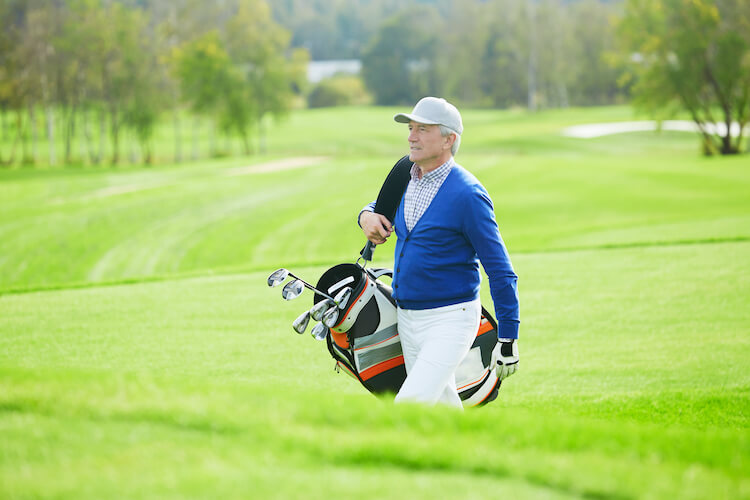 Senior man enjoying a game of golf, an outdoor activity to enjoy in the summer.