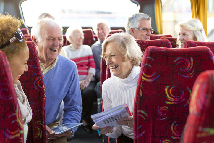 Senior couples laugh together on a tour bus